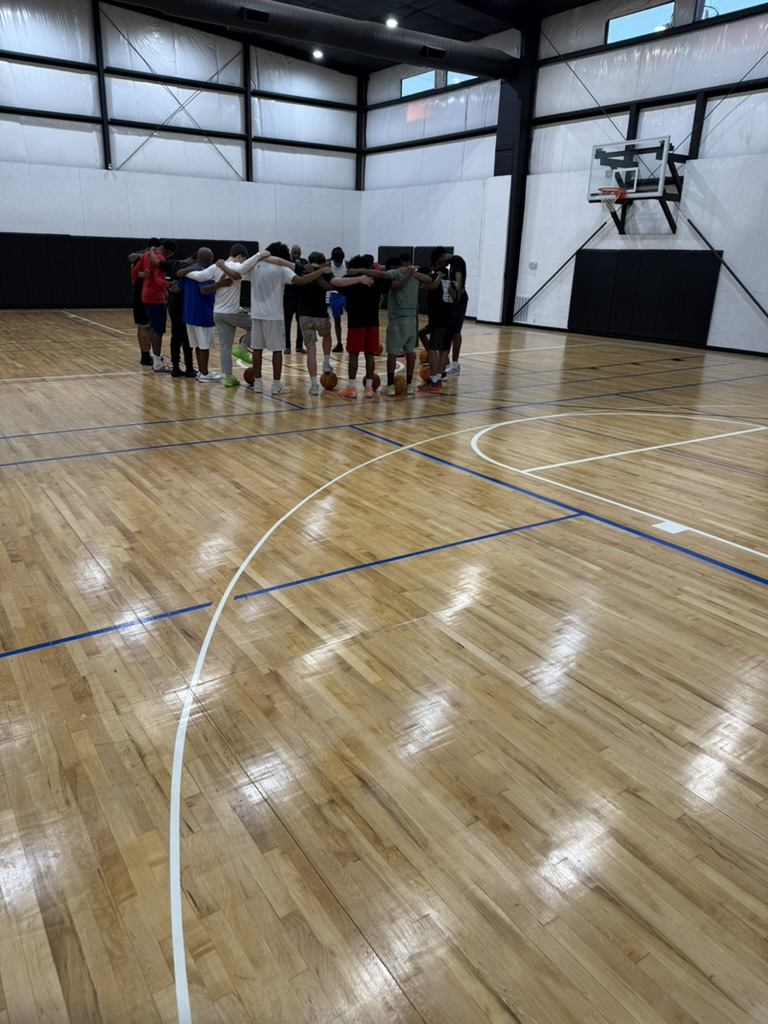 Players and coaches in a prayer huddle at center court